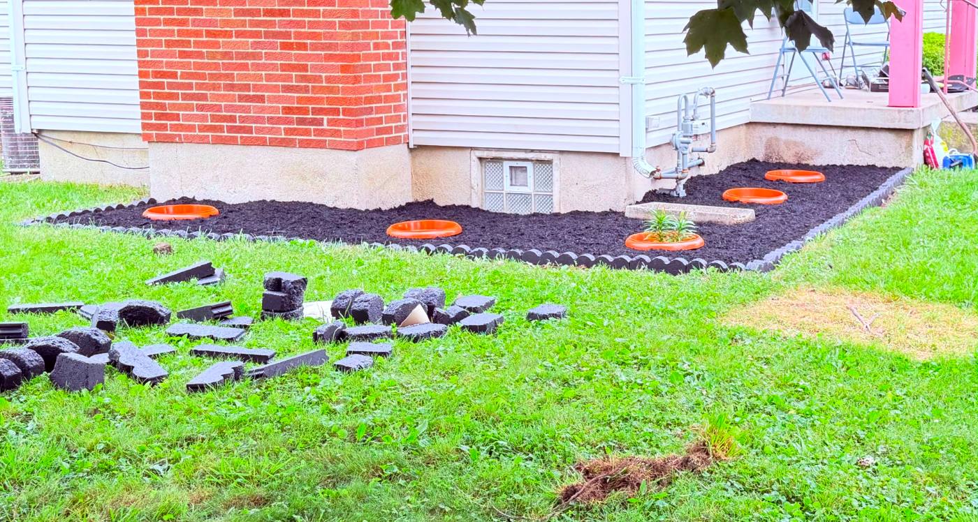 Bed maintenance and mulch installation — finished landscape bed with stone edging and planters